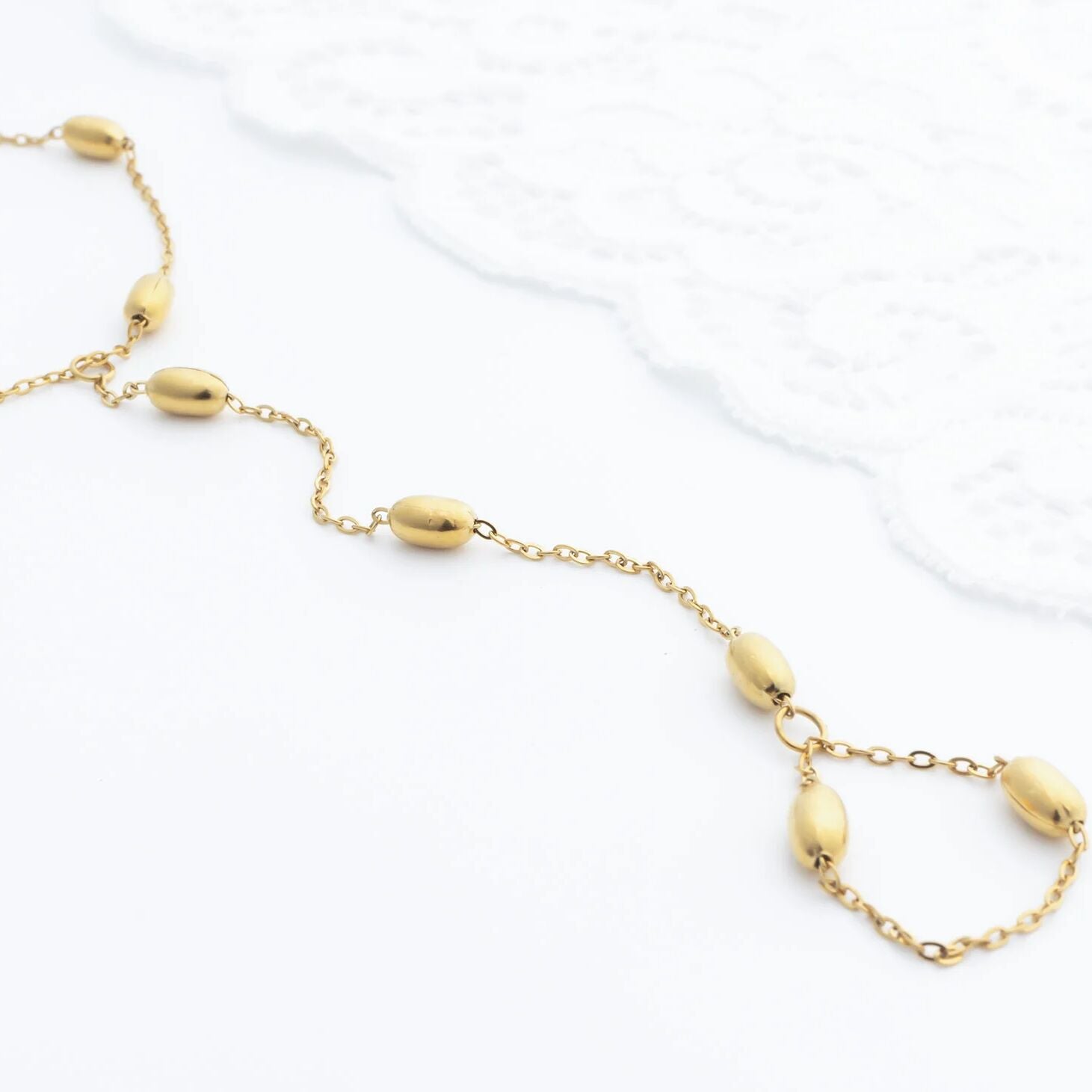 Gold Statement Bead Hand Chain with round beads on a white background