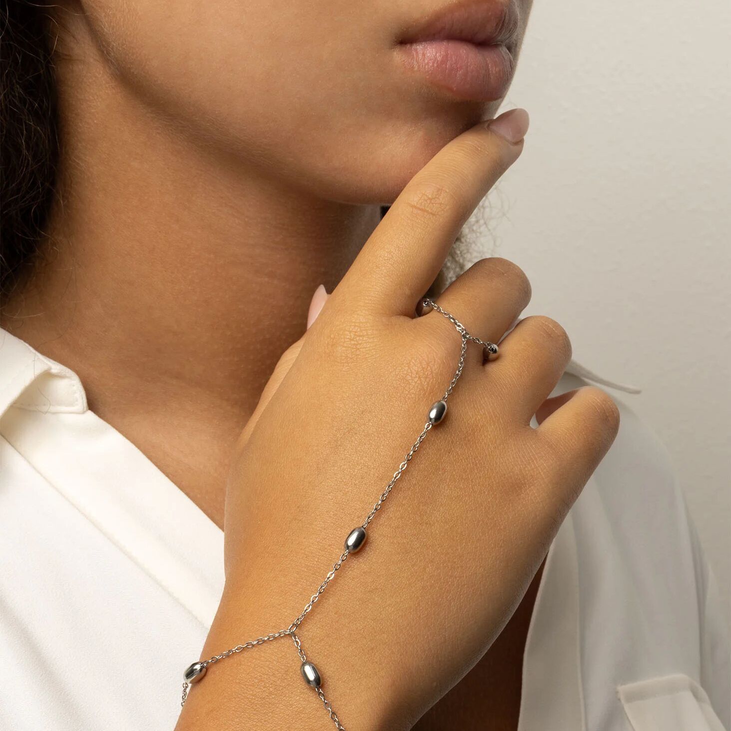 Close-up of a hand wearing a delicate silver Statement Bead Hand Chain with small beads.