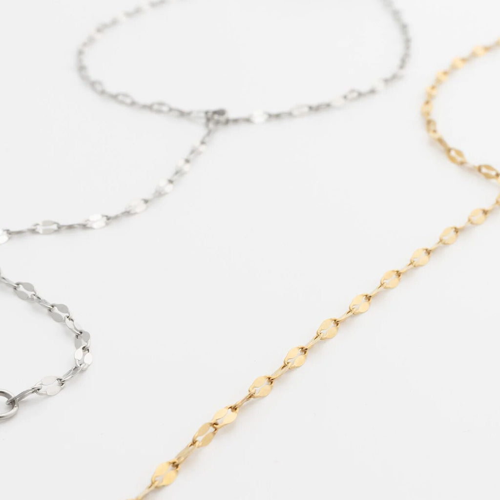 Two gold and silver Lip Hand Chains on a light gray background