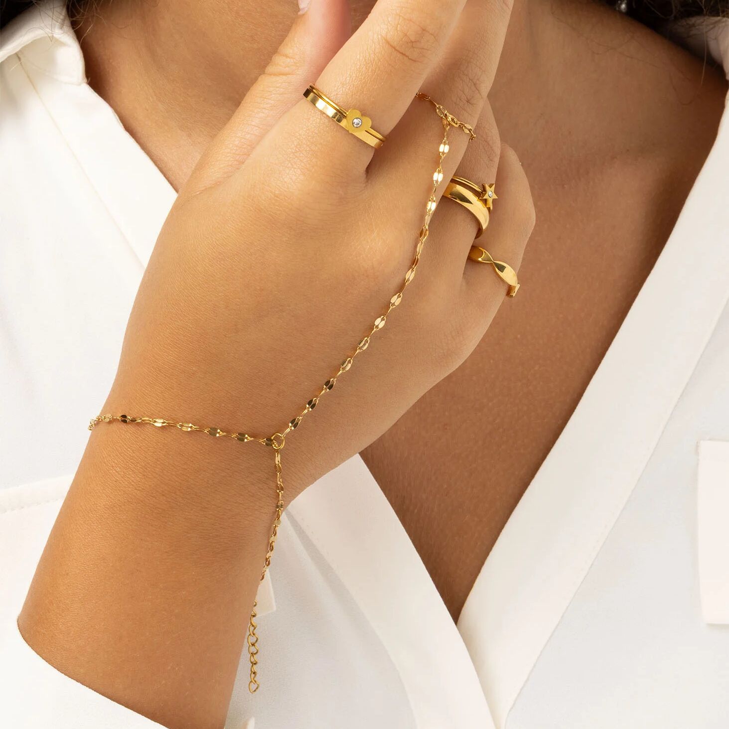 Gold Lip Hand Chain and rings on a hand against a white background