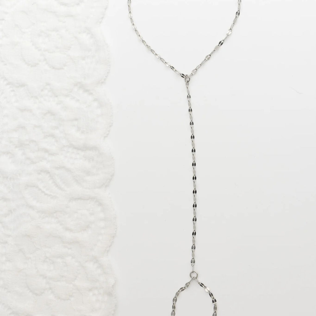 Silver beaded Lip Hand Chain on a textured white background