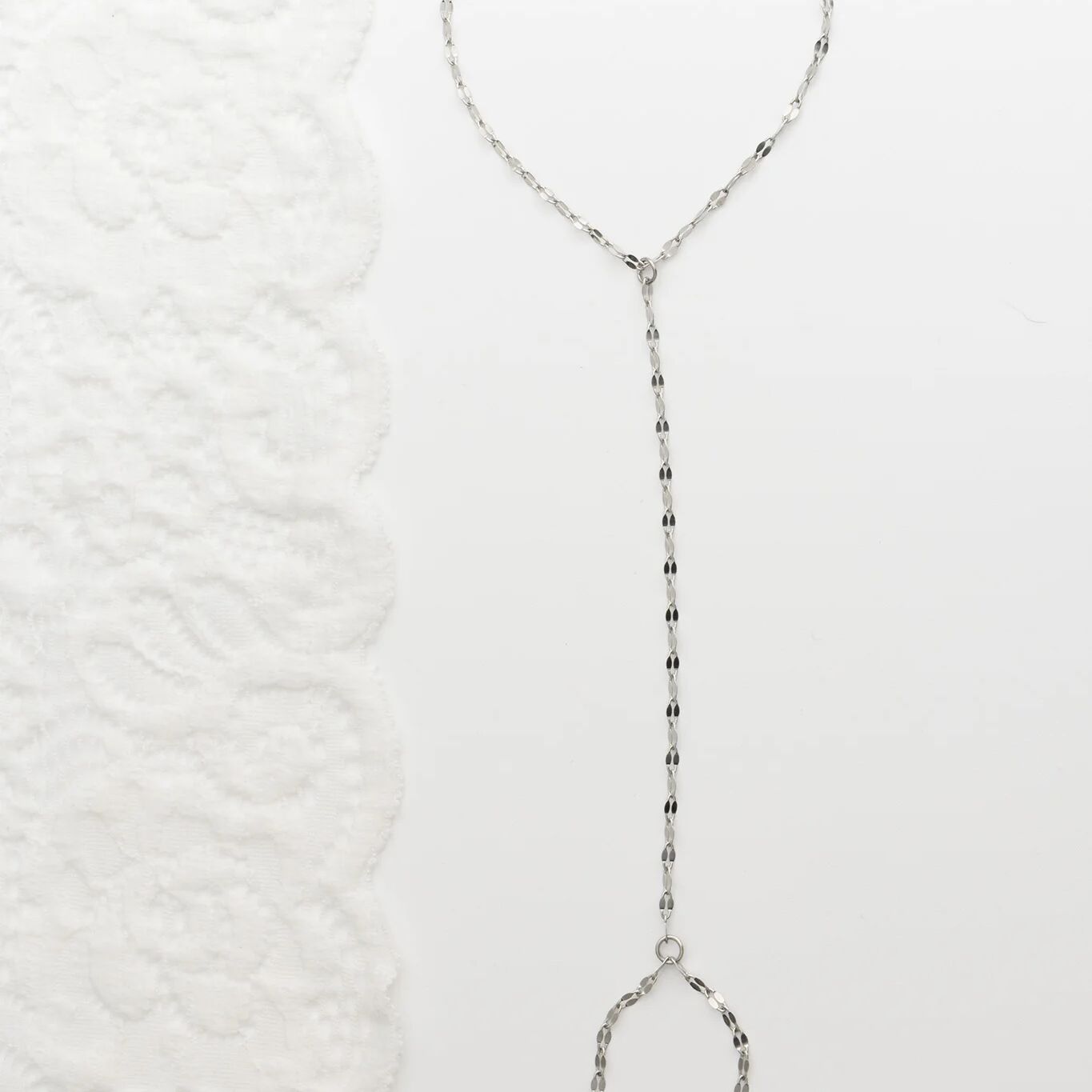 Silver beaded Lip Hand Chain on a textured white background