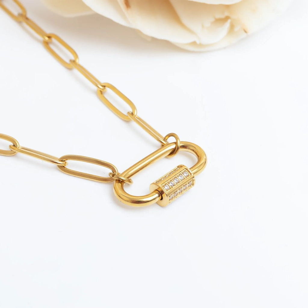 Gold chain necklace with a lock clasp on a light background
