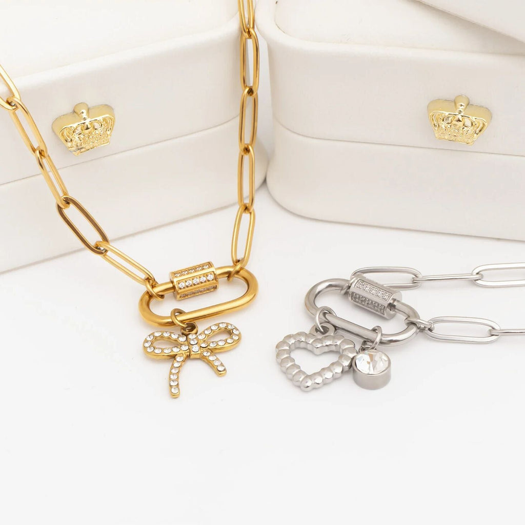Gold and silver necklaces with charms on a white surface