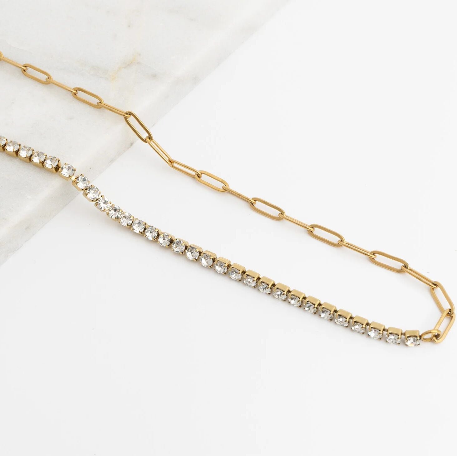 Gold chain necklace with embedded crystals on a white background