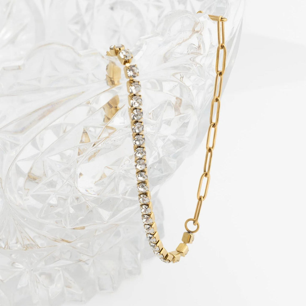 Gold bracelet with diamond accents on a textured white surface