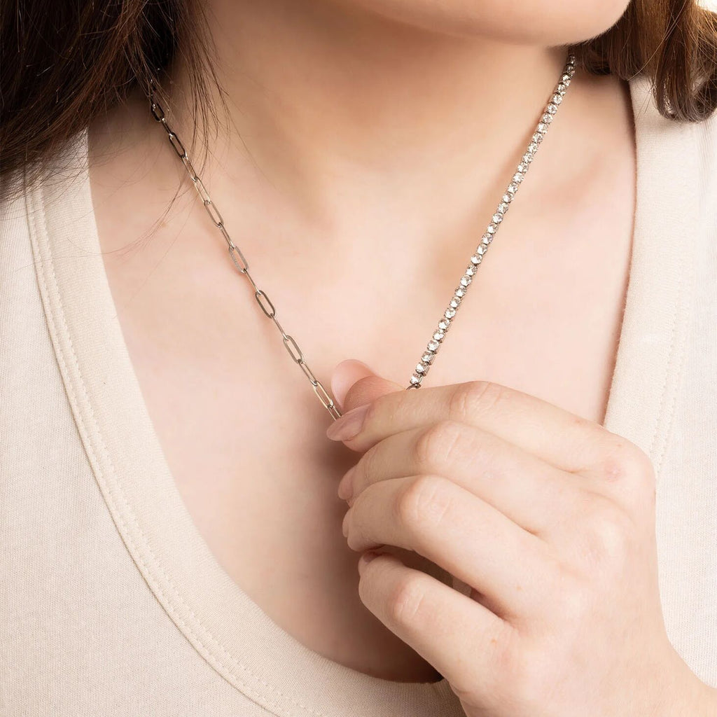 Close-up of a person wearing a delicate silver necklace with a blurred background