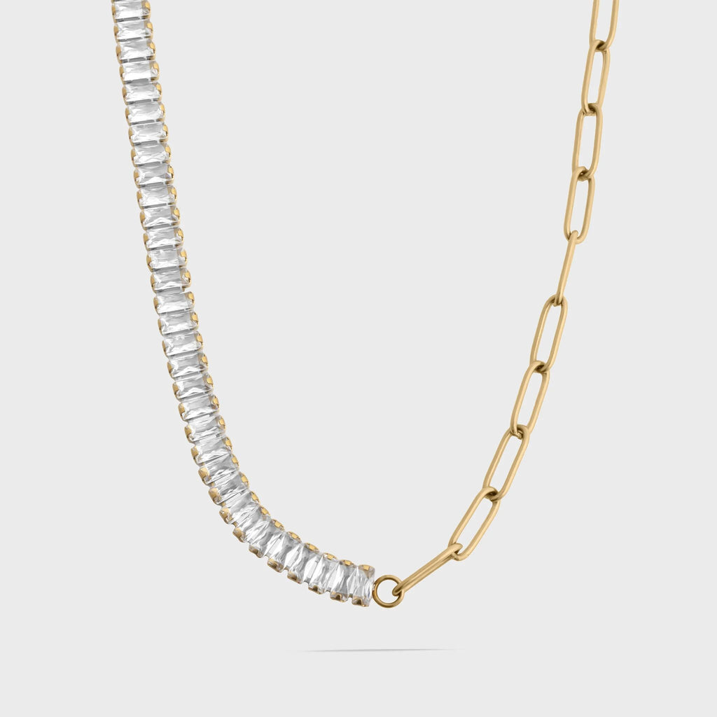 Gold necklace with clear gemstones on a light gray background
