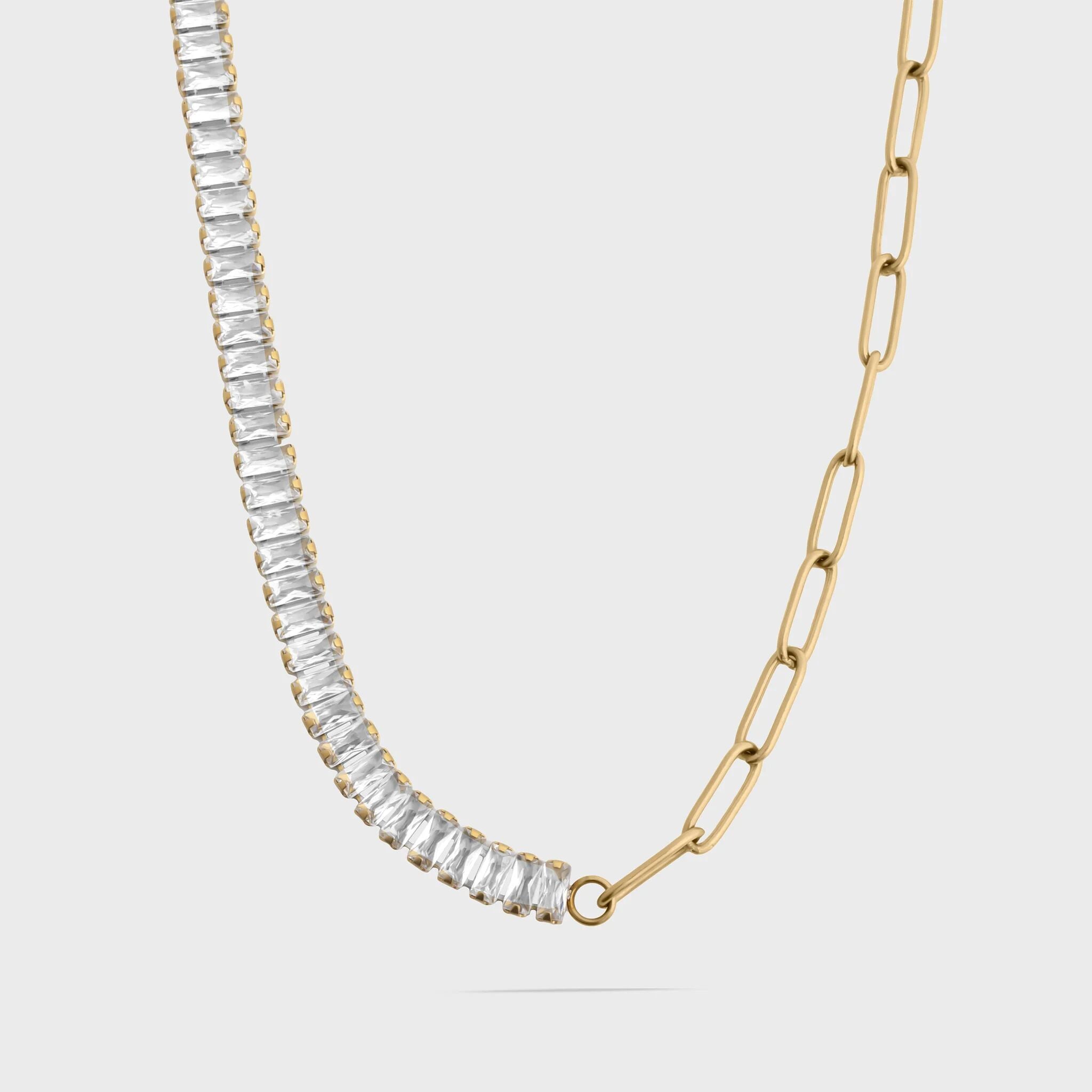 Gold necklace with clear gemstones on a light gray background