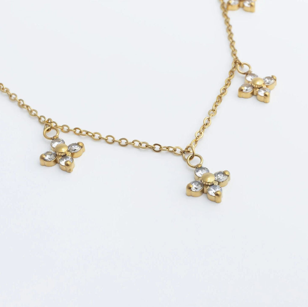 Gold necklace with clover-shaped pendants on a white background