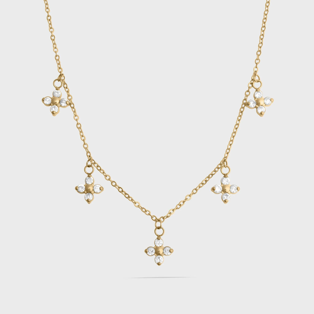 Gold necklace with floral pendants on a light gray background