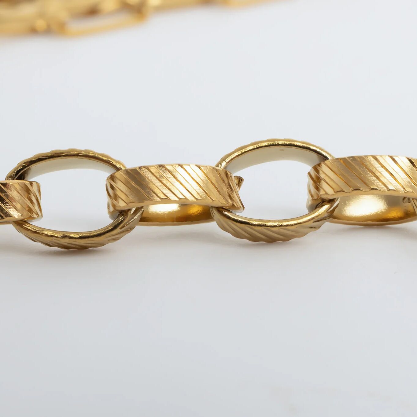 Close-up of a gold chain on a light gray background