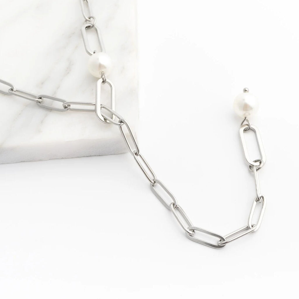 Silver y-shaped chain necklace with pearl-like beads on a white background