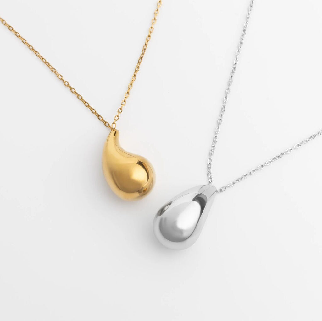 Gold and silver teardrop-shaped pendants on chains against a white background