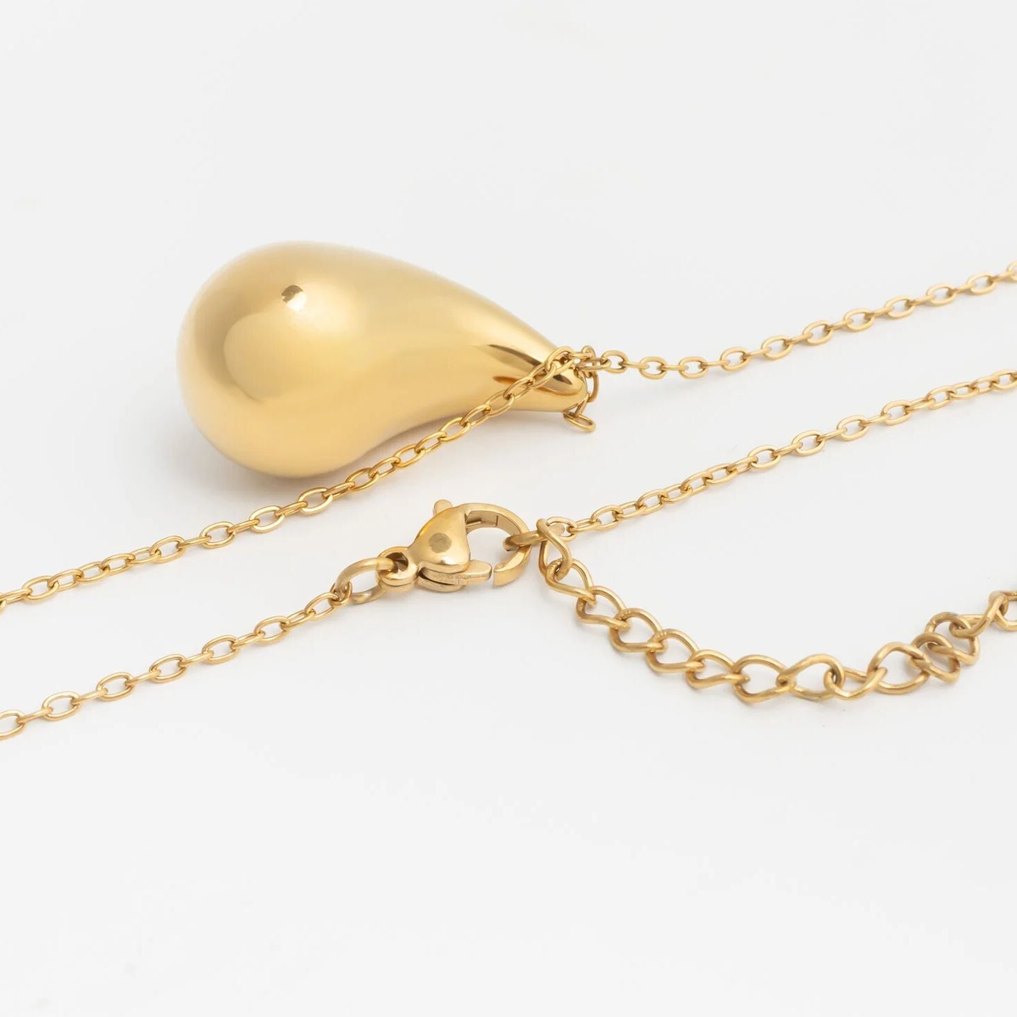 Gold necklace with a teardrop-shaped pendant on a white background