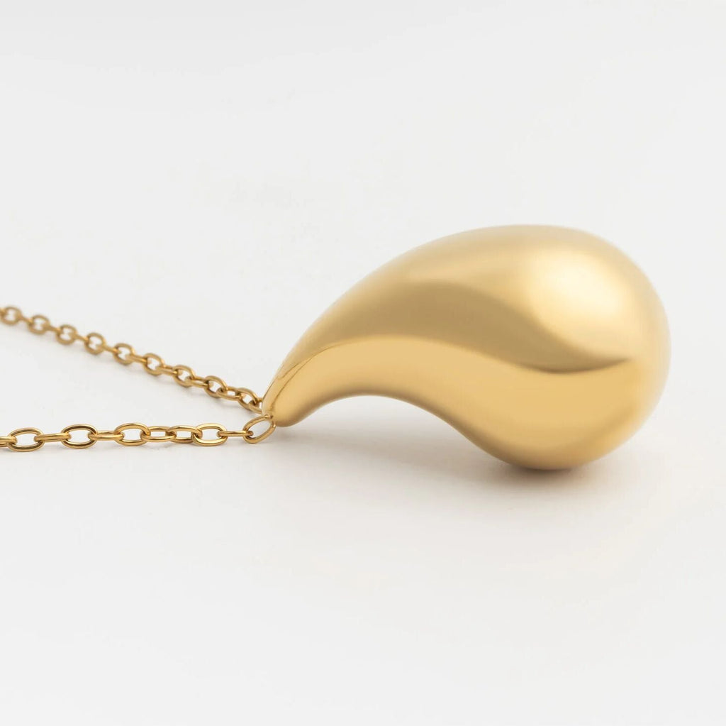 Gold teardrop pendant necklace on a light gray background