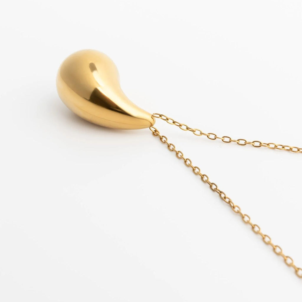 Gold teardrop-shaped pendant on a chain against a white background