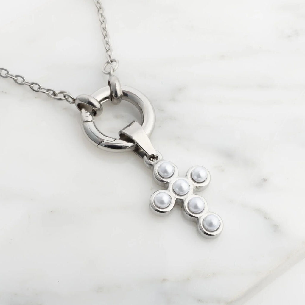 Silver charm holder necklace with a unique cross pendant on a light marble background