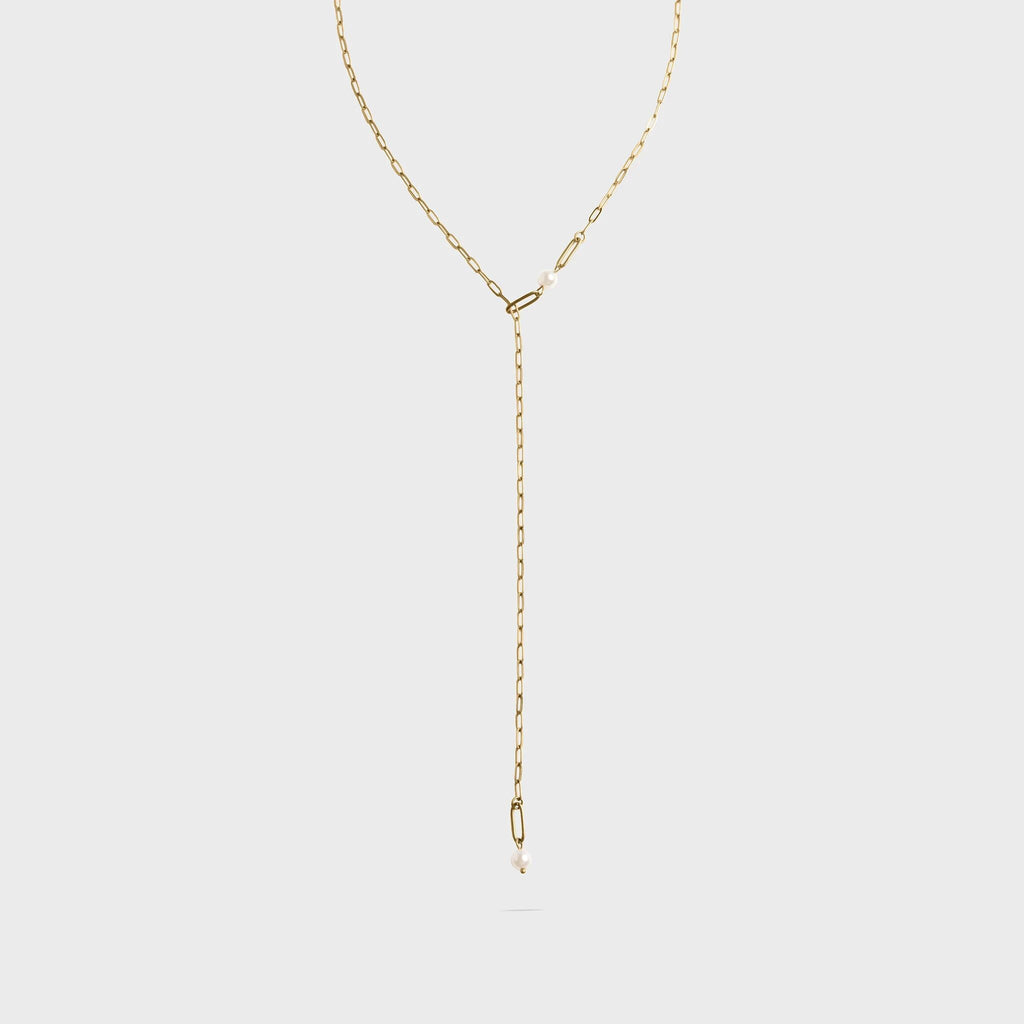 Gold lariat necklace on a light gray background