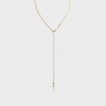 Gold lariat necklace on a light gray background