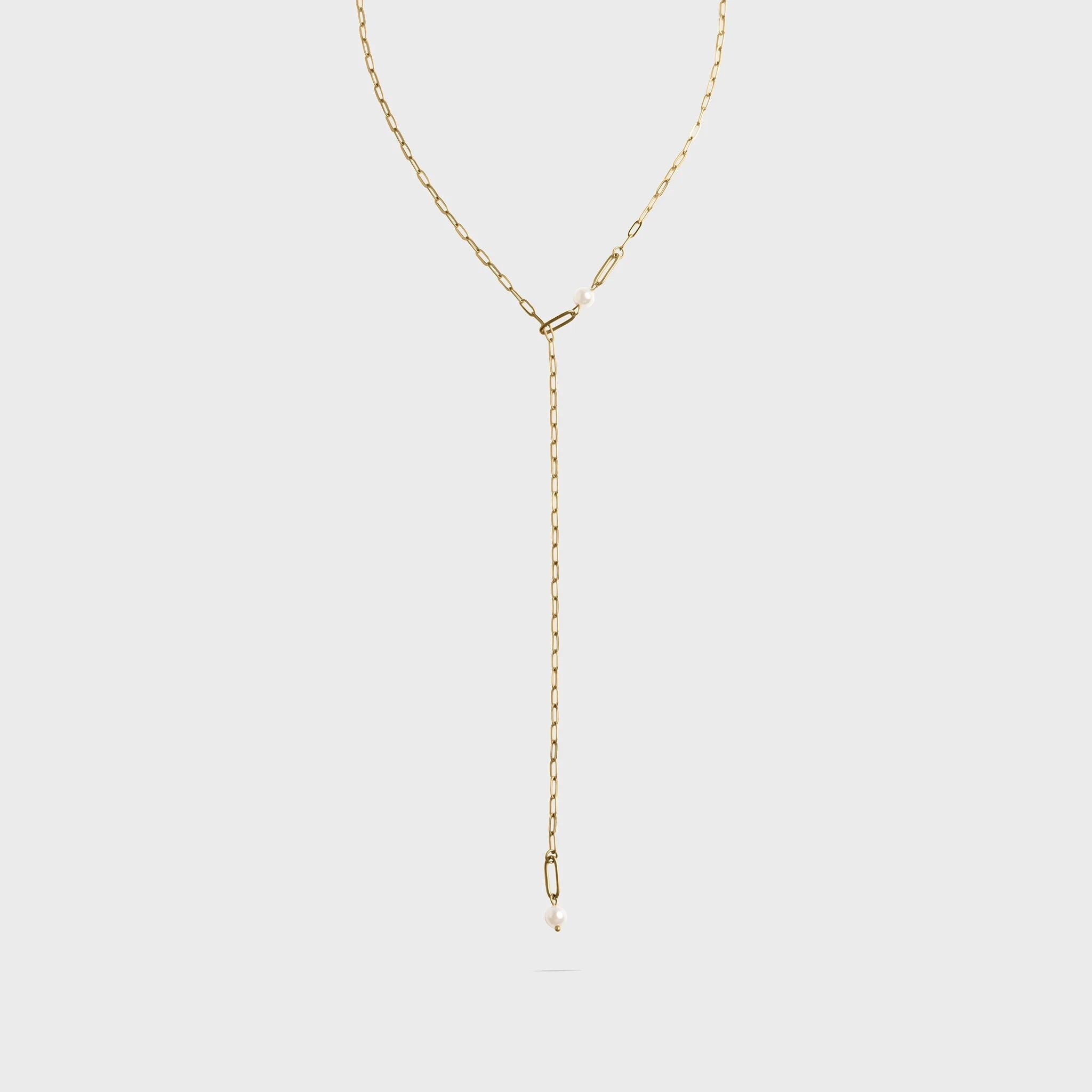 Gold lariat necklace on a light gray background