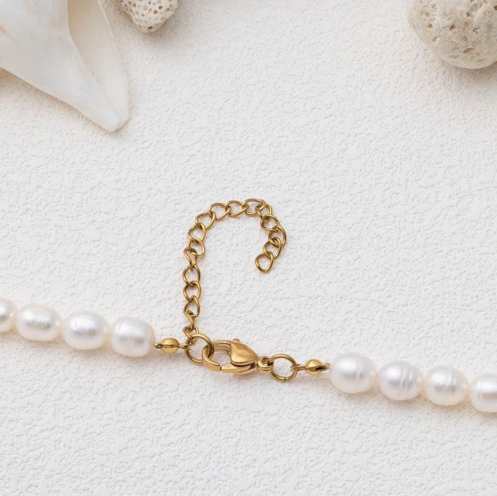 Pearl necklace with gold clasp on a light background