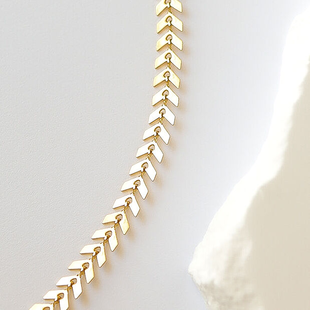 Gold chevron chain earring on a white background