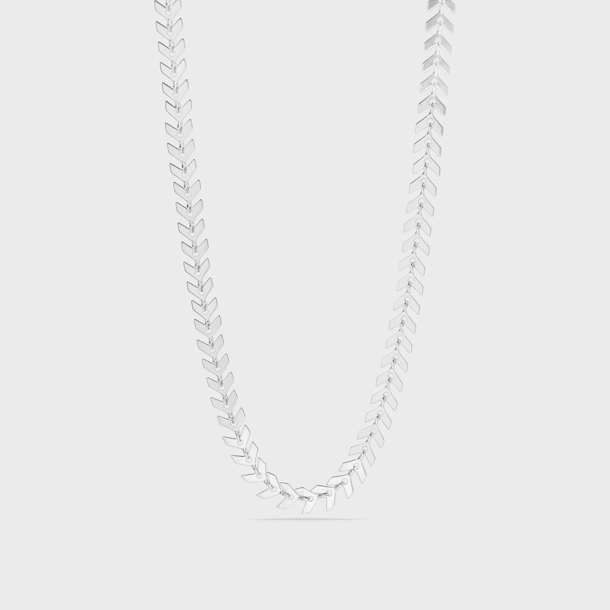 Silver necklace with leaf-like pendants on a light gray background