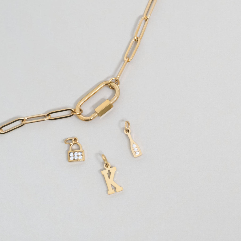 Gold carabiner charm holder and lock, letter, and champagne bottle charms