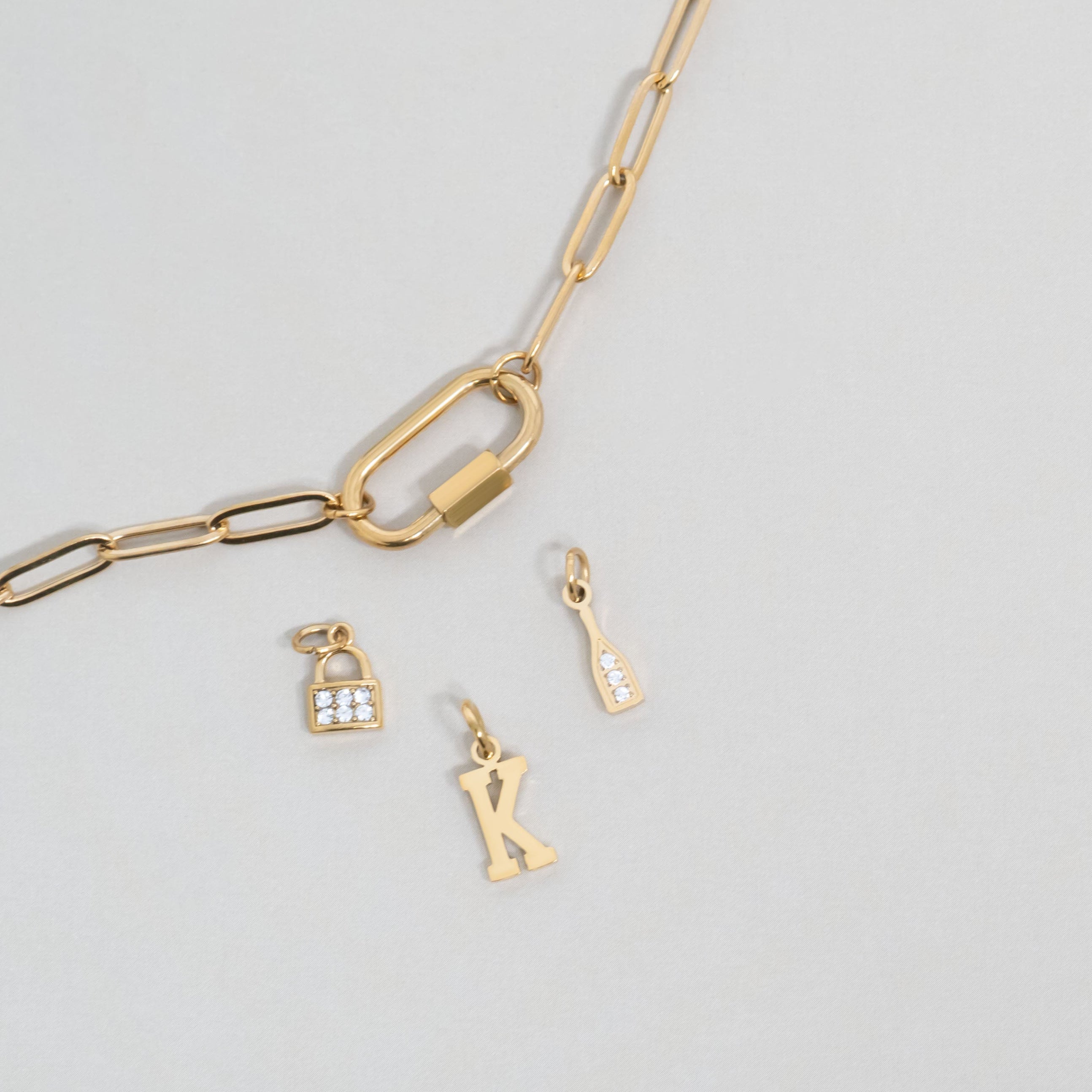 Gold carabiner charm holder and lock, letter, and champagne bottle charms