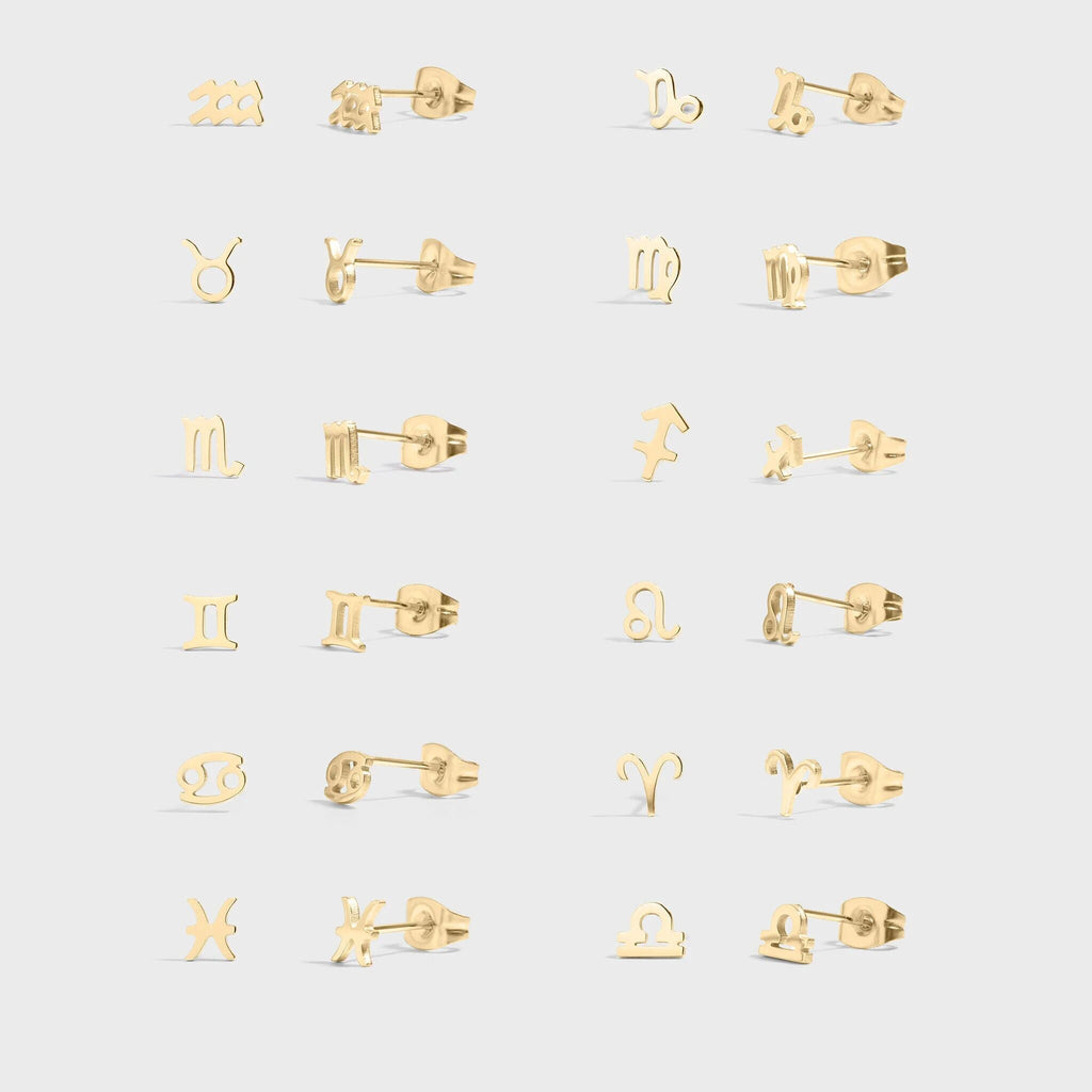 Set of gold earrings with zodiac symbols on a light gray background