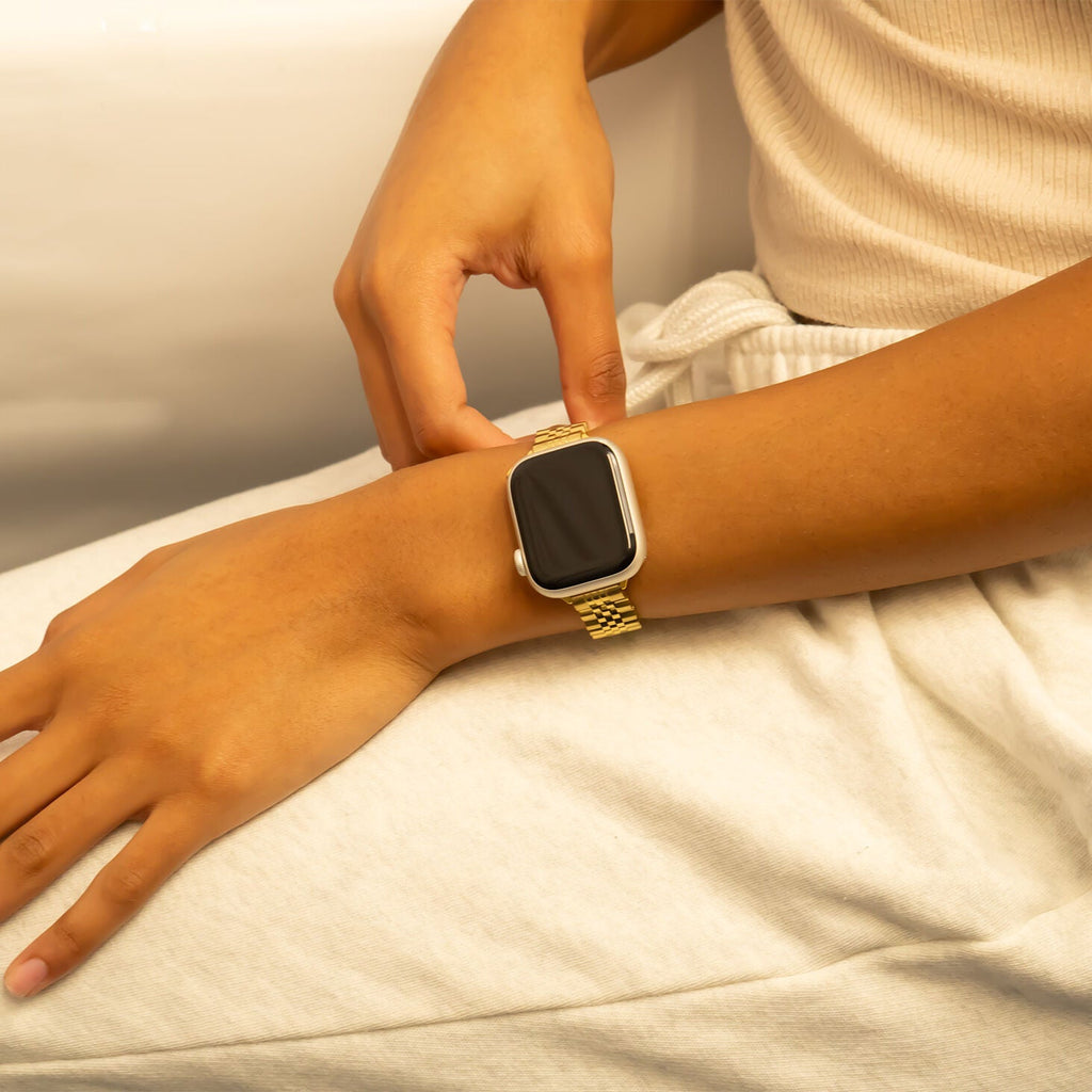 Person wearing a gold smartwatch on a neutral background