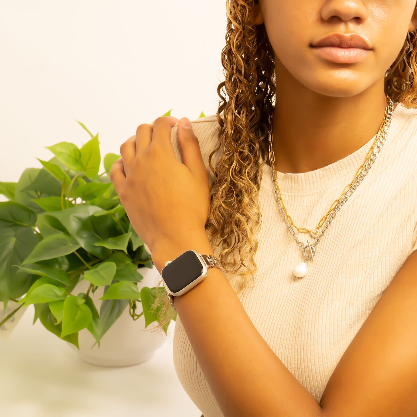 Woman wearing a smartwatch with a plant in the background
