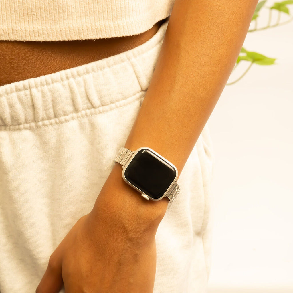 Person wearing a silver smartwatch on a blurred background