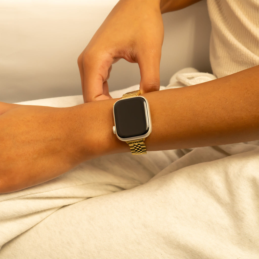 Person wearing a gold smartwatch on a neutral background