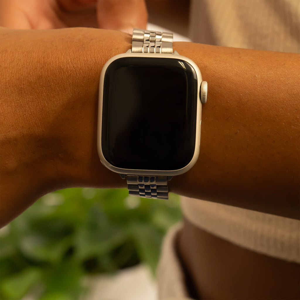 Silver smartwatch on a wrist with a blurred green background