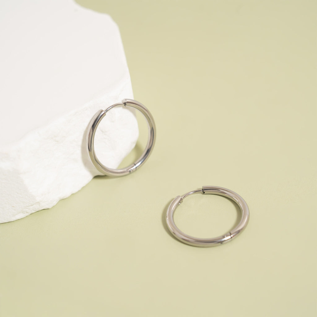 Silver hoop earrings on a light green background