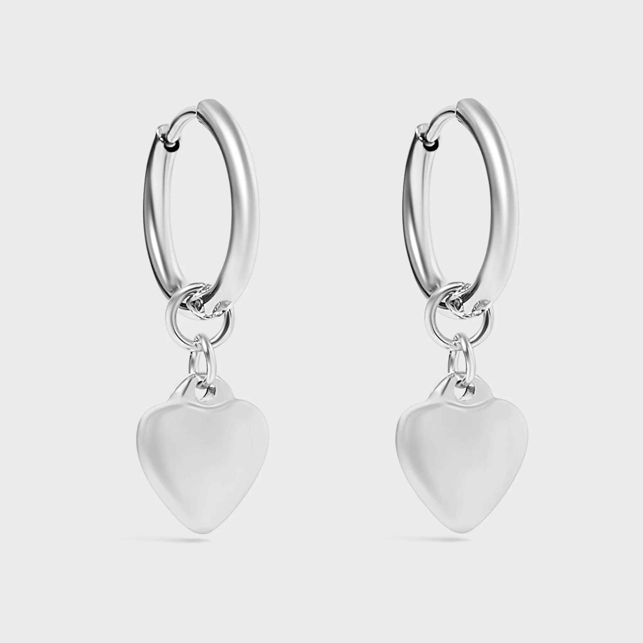 Silver hoop earrings with heart-shaped charms on a light gray background