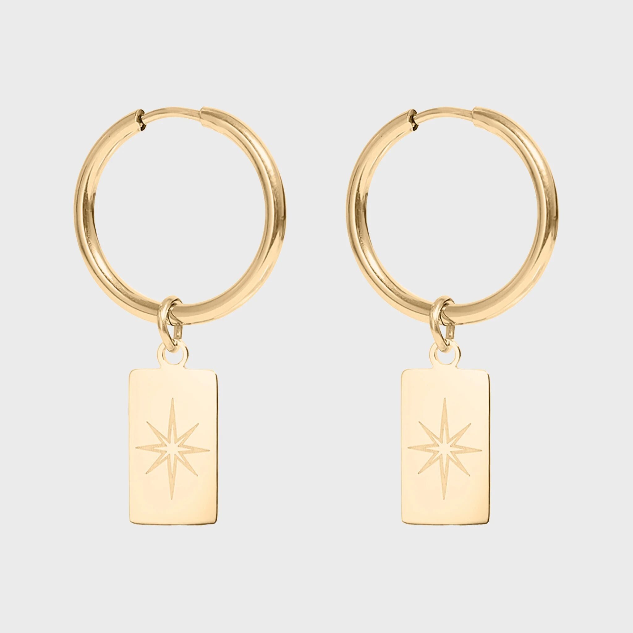 Gold hoop earrings with star-shaped charms on a light gray background