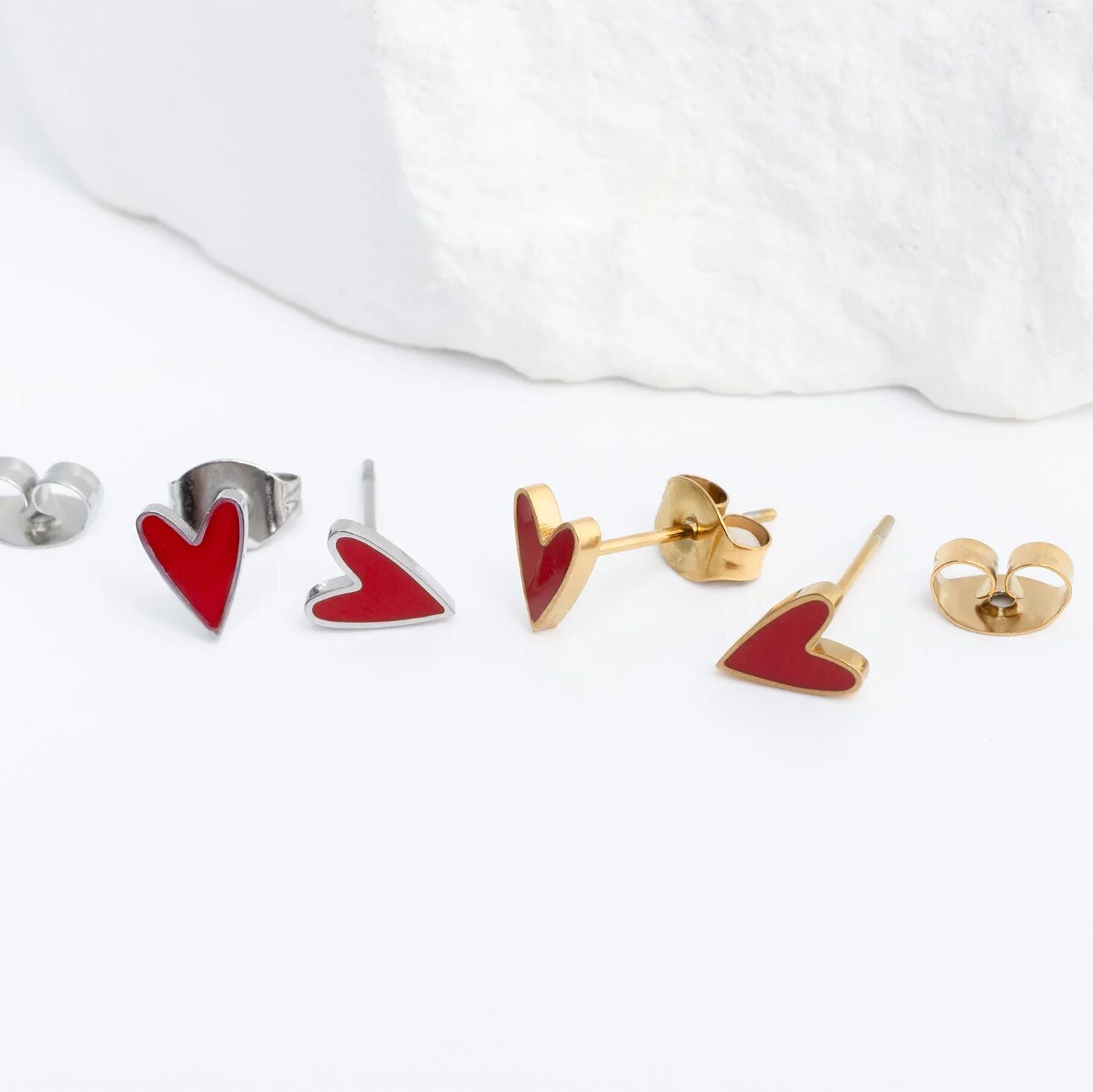 Heart-shaped earrings in red and gold on a white background