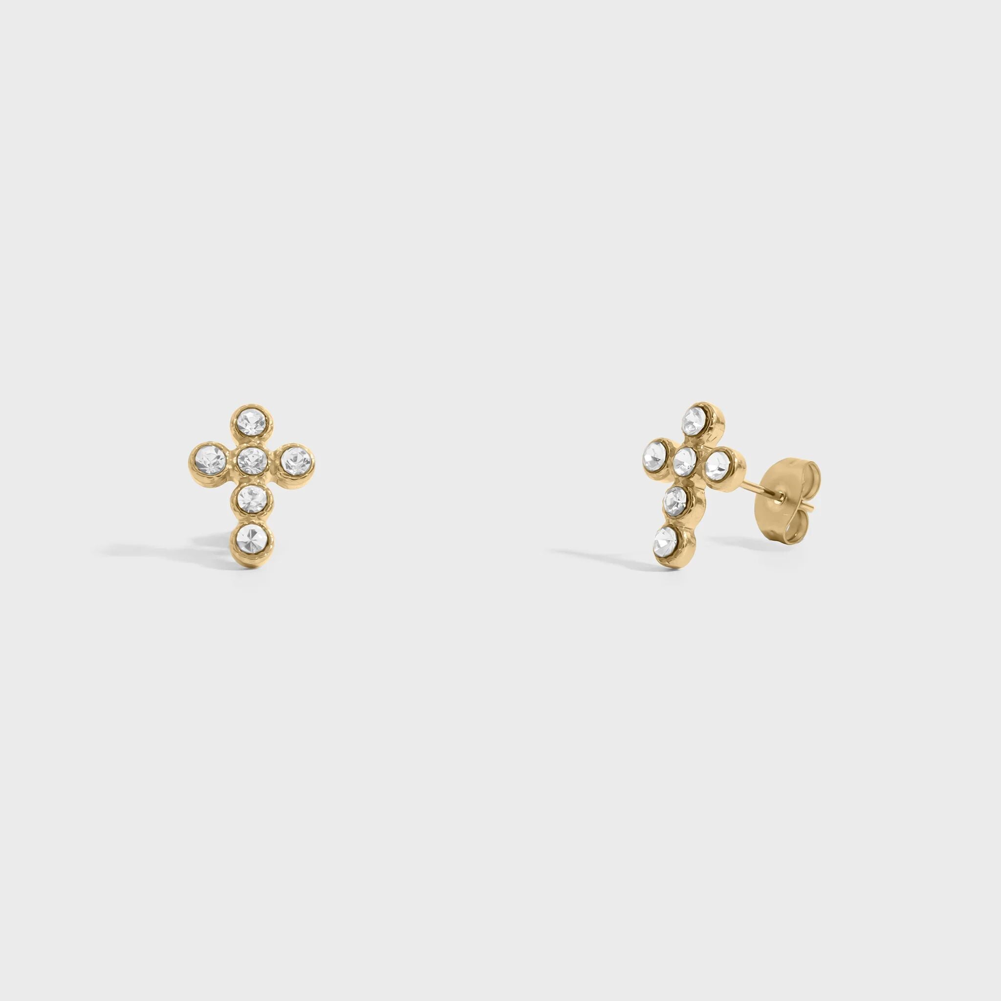 Gold cross-shaped earrings with small stones on a light gray background