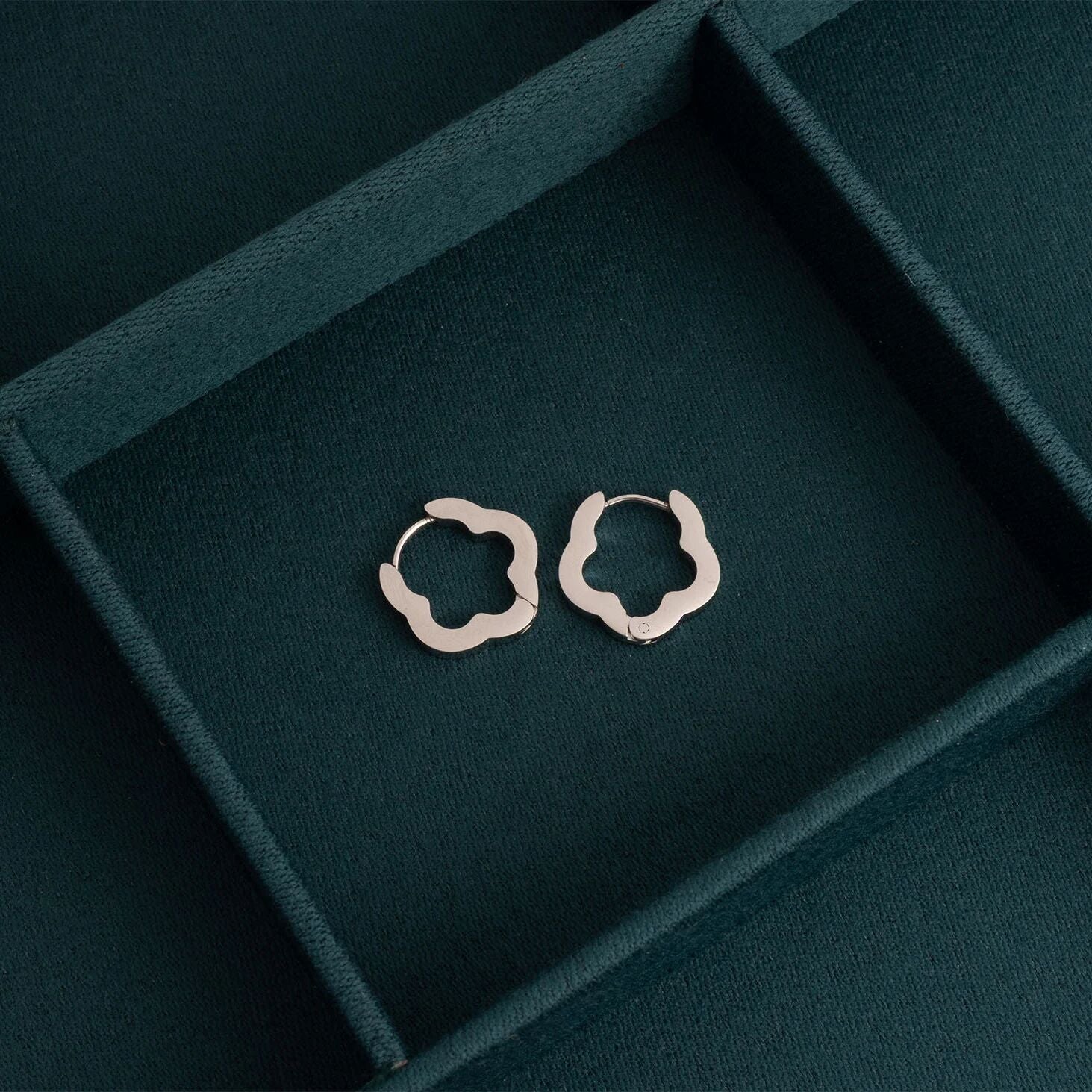 Silver hoop earrings on a dark green jewelry box