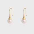 Pair of pearl earrings with gold hooks on a light gray background