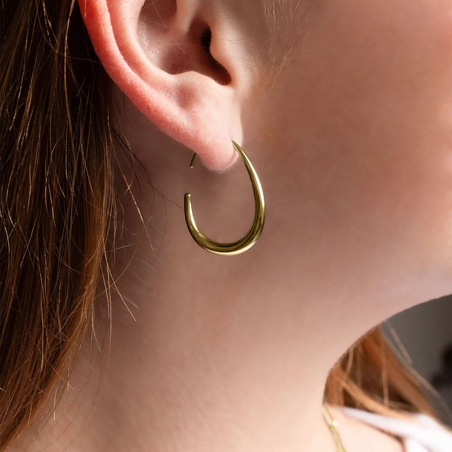 Close-up of a gold hoop earring worn by a person.