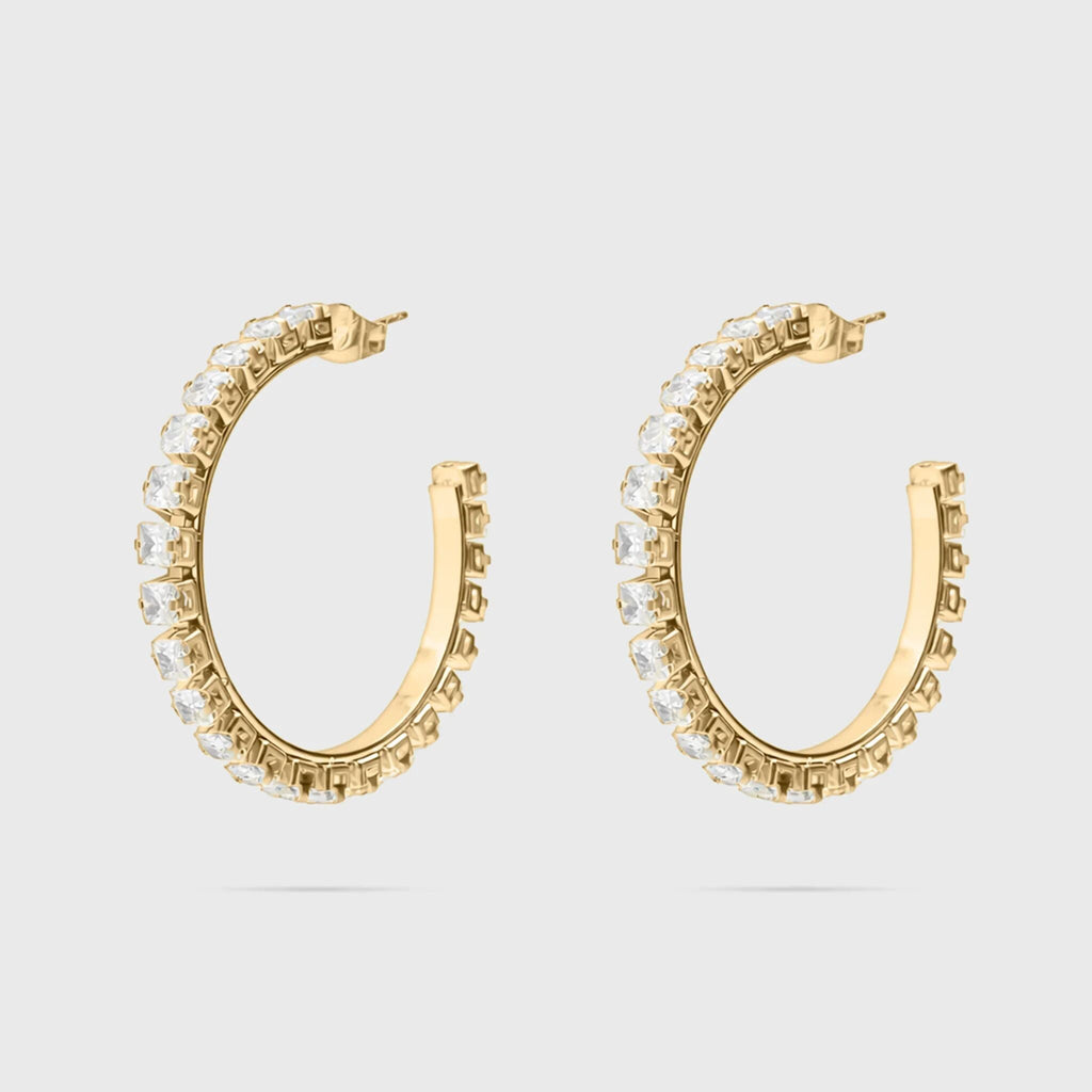 Gold hoop earrings with clear gemstones on a light gray background