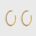 Gold hoop earrings with clear gemstones on a light gray background