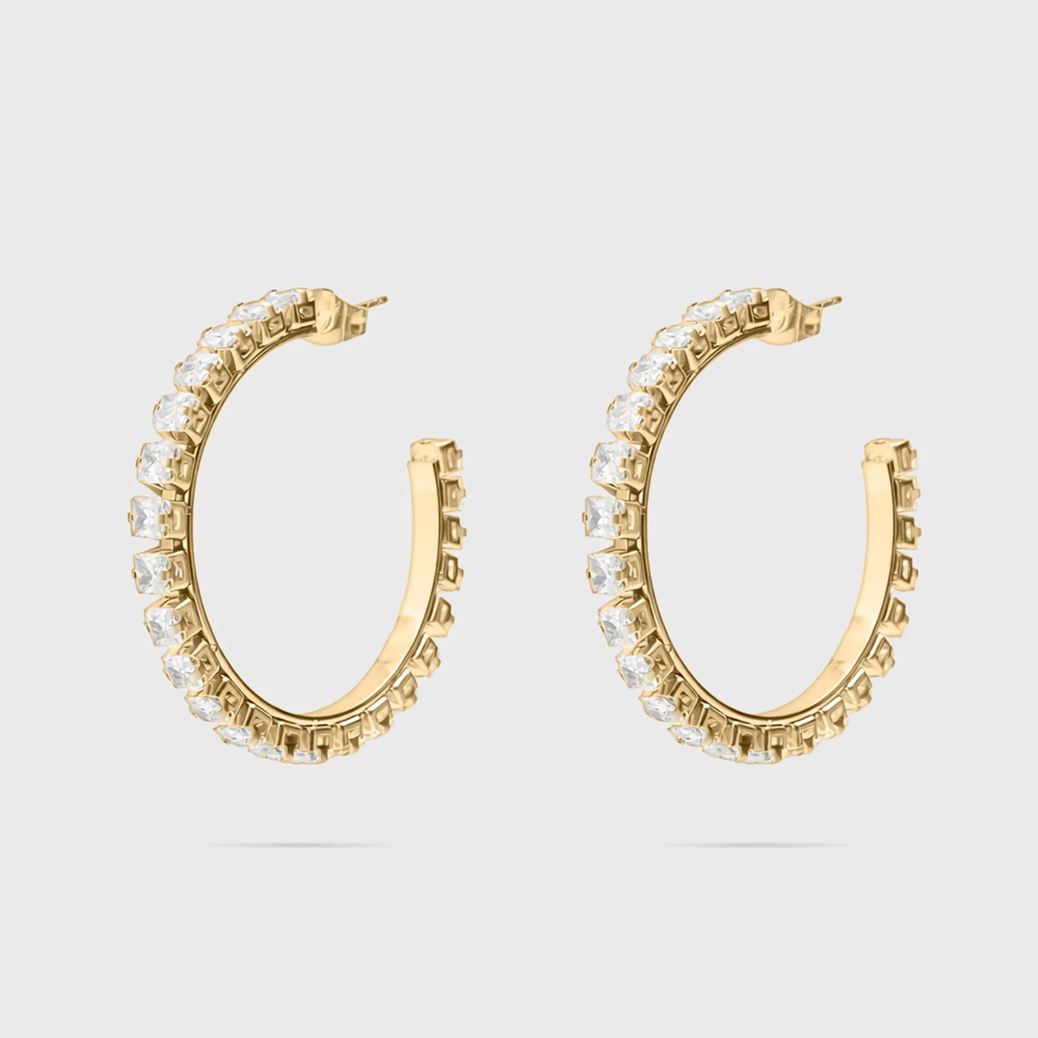 Gold hoop earrings with clear gemstones on a light gray background