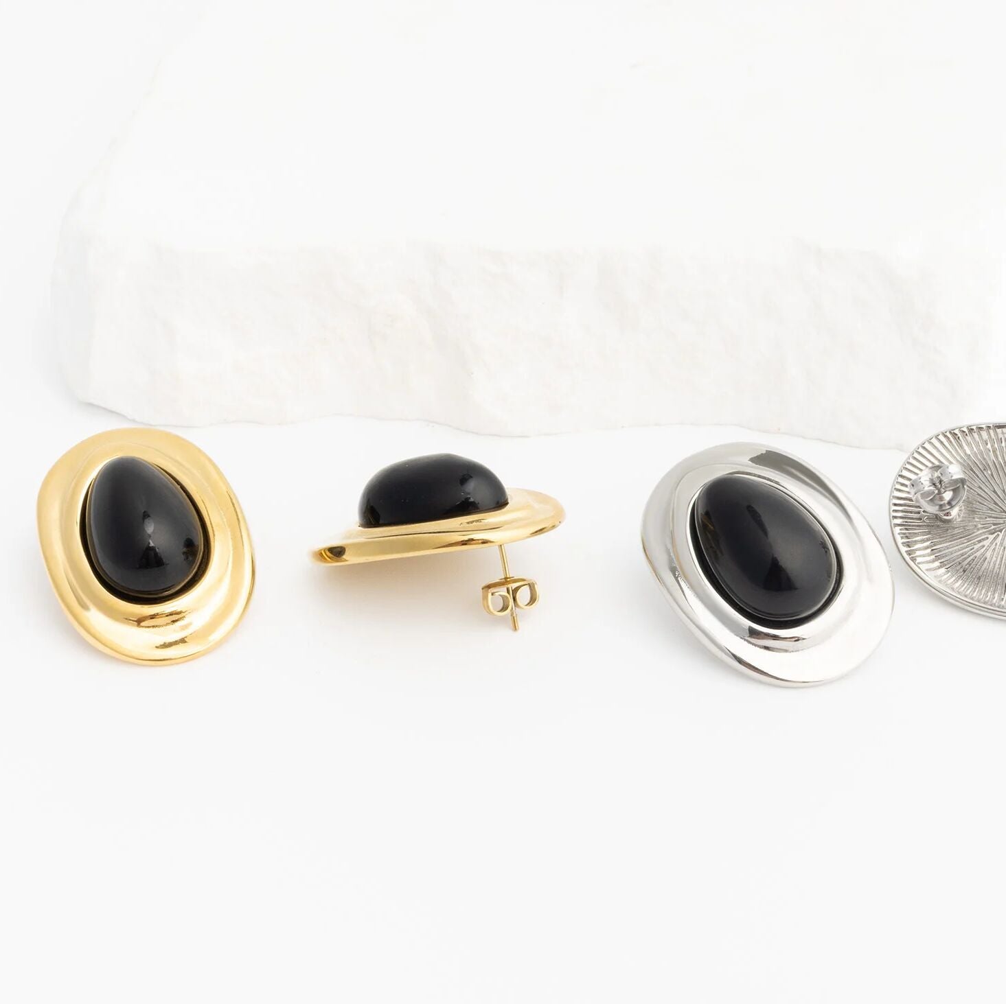 Pair of black stone Black Enamel Stud Earrings with gold and silver metal backs on a white background