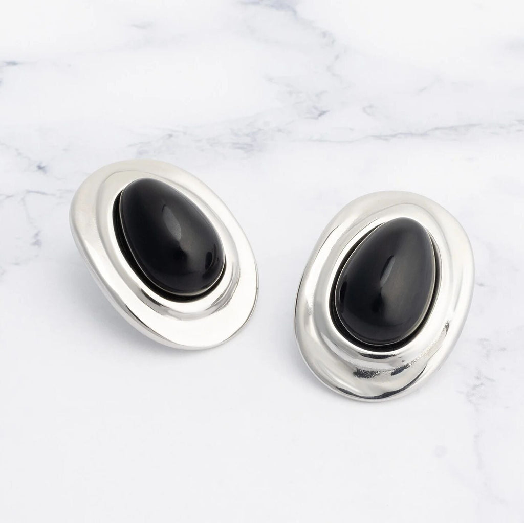 Pair of silver Black Enamel Stud Earrings with black stones on a marble surface
