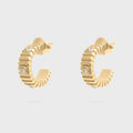 Gold hoop earrings with small diamonds on a light gray background